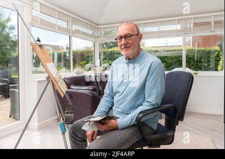 Umweltportrait eines älteren Mannes, der in seinem Atelier mit Aquarellen malte Stockfoto