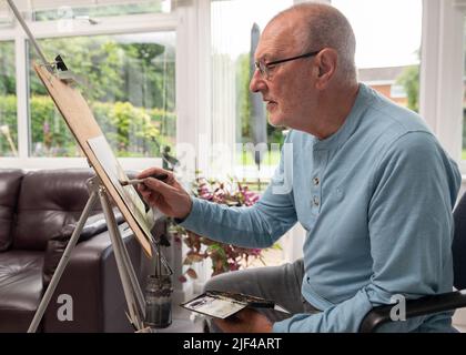 Umweltportrait eines älteren Mannes, der in seinem Atelier mit Aquarellen malte Stockfoto