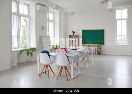 Einrichtung eines modernen Klassenzimmers mit Schreibtischen, Stühlen, Tafel und Whiteboard Stockfoto