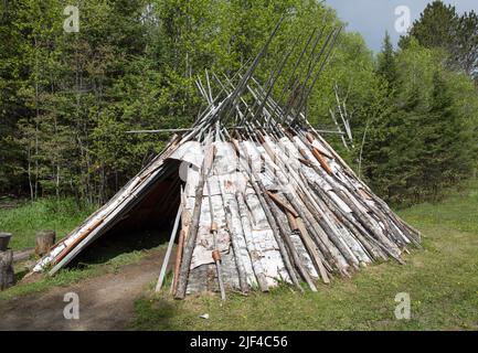 Eine Nachbildung eines Ojibwa-, Ojibwe- oder Anishinaabe-Wigwams aus Birkenrinde in ovaler Form, der am Grand Portage National Monument im Norden von Minnesota, USA, wohnt Stockfoto