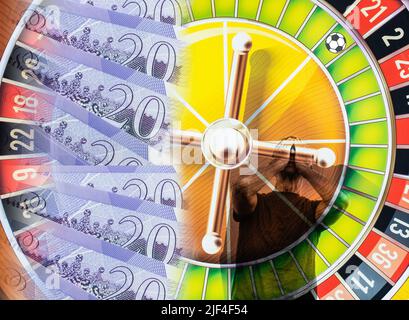 Zwanzig Pfund-Noten auf Roulette-Rad mit Mann mit Händen über Gesicht. Fußball auf Roulette-Rad. Glücksspiel, Fußball, Online, psychische Gesundheit... Konzept Stockfoto