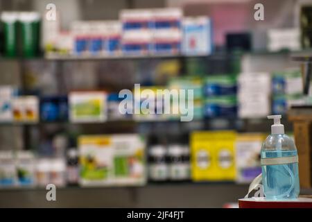 Händedesinfektionsmittel-Gel am Eingang eines verschwommenen Ladens, neue Gewohnheit in der Ära der Covid Stockfoto