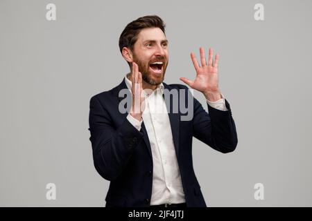 Positiver Geschäftsmann mit Bart legt seine Hände an die Seite seines Mundes und schreit Stockfoto