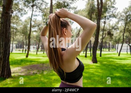 Brünette sportliche Frau trägt schwarzen Sport-BH stehen auf Stadtpark, im Freien Band ihre Haare in einem Pferdeschwanz während Sie einige Training. Stockfoto