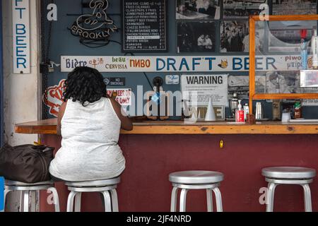 Kundin, die am Barschalter im Vergnügungspark-Restaurant der Paul'd-Tochter im Stadtteil Coney Island in Brooklyn, New York City, USA, sitzt Stockfoto
