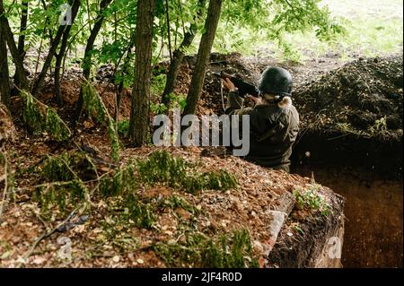 Ein Soldat in einem Graben an der Front des ukrainisch-russischen Krieges, die Verteidigung der ukrainischen Grenzen vor Orks, eine Kriegerin. Stockfoto