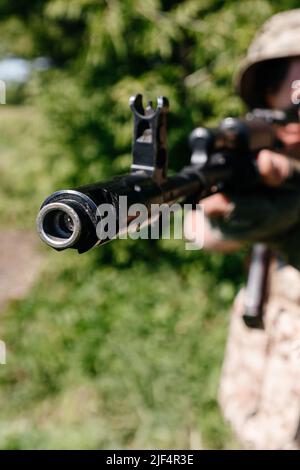 Ein Soldat mit einem Kampf militärischen Sturmgewehre AK 74 steht auf einem Feld, ukrainische Weizenfelder und Krieg, Mündungsbremskompensator und Sicht auf die aut Stockfoto