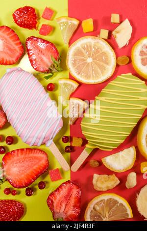 Zwei Eiscremes auf einem Stock - Erdbeere und Zitrone auf gelbem und rotem Hintergrund. Sommerliche Fruchtdesserts Stockfoto