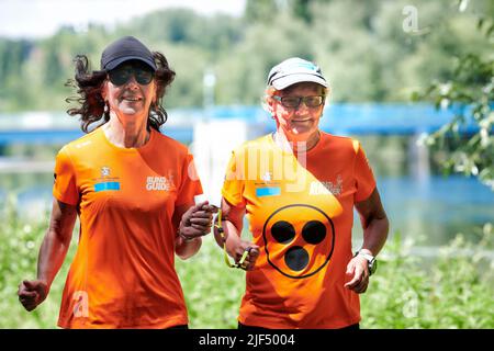 Sehbewehrte Joggerin mit ihrer weiblichen Laufguide. In einigen werden Laufguides for bilinde and sehbeeintraechtigte Laeuferinnen ausgestellt Stockfoto