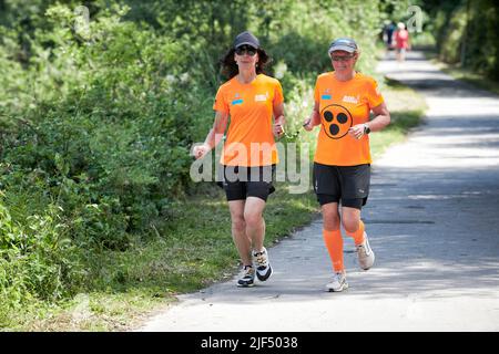 Sehbewehrte Joggerin mit ihrer weiblichen Laufguide. In einigen werden Laufguides for bilinde and sehbeeintraechtigte Laeuferinnen ausgestellt Stockfoto