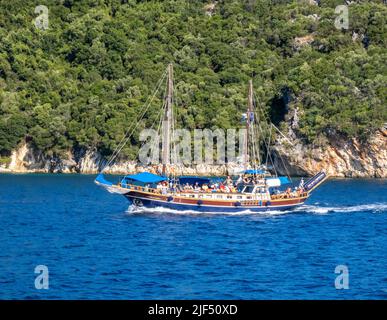 Frau Christina segelt entlang der Küste von Lefkada auf den ionischen Inseln Griechenlands mit begeisterten Urlaubsausflüglern, die kleinere Inseln besuchen Stockfoto