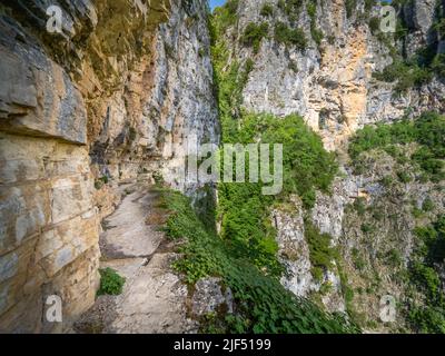 Enger, prekärer Pfad, der in die schiere Felswand hinter dem Kloster Agia Paraskevi hoch über der Vikos-Schlucht in der Region Zagori in Griechenland eingehauen ist Stockfoto