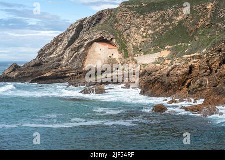 Die Eremitage von Santa Justa ist in den Felsen einer Klippe über dem Kantabrischen Meer, der Stadt Ubiarco in Kantabrien, Spanien, gehauen Stockfoto