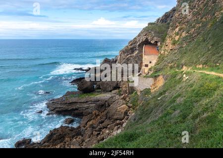 Die Eremitage von Santa Justa ist in den Felsen einer Klippe über dem Kantabrischen Meer, der Stadt Ubiarco in Kantabrien, Spanien, gehauen Stockfoto