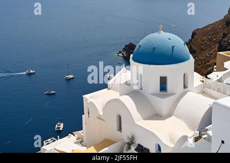 Oia, Santorini, Griechenland - 2022. Juni: Blaue Kuppel auf einer Kirche mit Blick auf das Meer in der Stadt Oia. Stockfoto