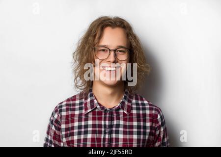 Porträt eines fröhlich lächelnden jungen Mannes, Student, mit Brille auf weißem Hintergrund. Stockfoto