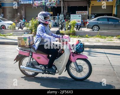 SAMUT PRAKAN, THAILAND, 19 2022. MÄRZ, Eine Frau fährt auf der Stadtstraße mit einem Motorrad Stockfoto