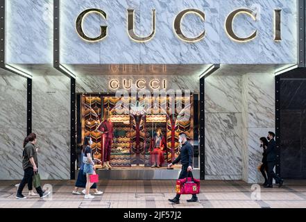 Shopper laufen am italienischen Luxusmodemarke Gucci-Logo vorbei und laden in Hongkong ein. Stockfoto