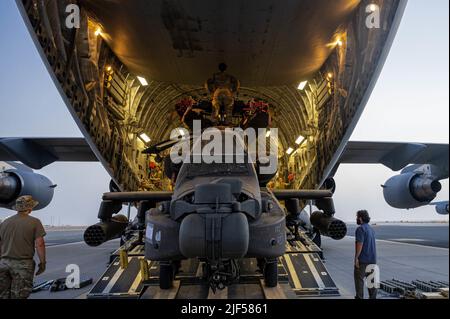 US-Luftwaffe vom Expeditionary Logistics Readiness Squadron 386. und US-Soldaten laden einen Apache-Hubschrauber auf einen C-17 Globemaster III auf der Ali Al Salem Air Base, Kuwait, 23. Juni 2022. Luftträger der 386. ELRS und Luftfahrtspezialisten der U.S. Army 11. Expeditionary Combat Aviation Brigade führten Hilfe an Stelle/Übertragung der Autorität von Apache-Hubschraubern durch, die dem U.S. Army 101. Aviation Bataillon zugewiesen wurden. (USA Luftwaffe Foto von Senior Airman Natalie Filzen) Stockfoto