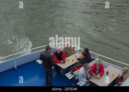 Ältere Touristen, Senioren, genießen Bier auf den Fährenbänken auf der malerischen Bingen-Rüdesheimer Flusskreuzfahrt durch den Mittelrhein. Stockfoto