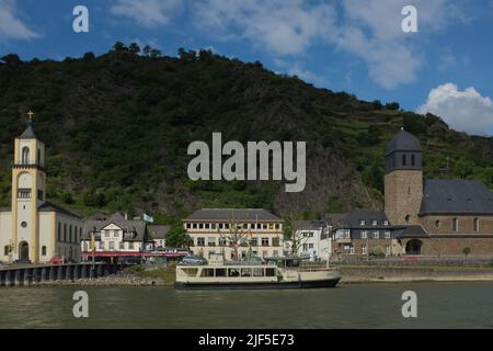 Die Fähre dockte in Sankt Goarshausen in Rheinland-Pfalz an. Vom Rhein aus hat man einen malerischen Blick auf die Stadtgebäude, Kirchen und einen Hügel. Stockfoto