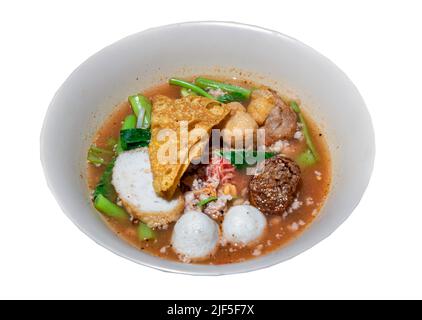 Yentafo Eiernudeln Suppe mit rosa Sauce und Fischbällchen, Garnelenkugel, gehacktes Schweinefleisch, gebratenes Wonton, gebratenen Taro und Morgenruhm in weißer Schüssel isoliert o Stockfoto