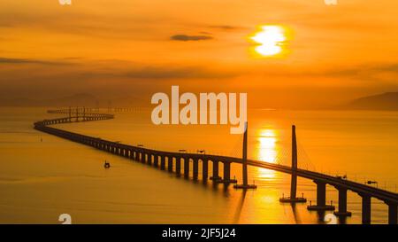 (220630) -- GUANGZHOU, 30. Juni 2022 (Xinhua) -- Luftfoto vom 7. August 2019 zeigt eine Ansicht der Hong Kong-Zhuhai-Macao Brücke bei Sonnenaufgang, Südchina. Die 55 Kilometer lange Brücke, die sich in den Gewässern von Lingdingyang der Mündung des Pearl River befindet, ist die längste Brücke-Tunnel-kombinierte Cross-Sea-Passage der Welt. Mit dem Bau von Verkehrsadern wurde die Konnektivität in der Region Guangdong-Hong Kong-Macao Greater Bay kontinuierlich verbessert. Das bequeme Verkehrsnetz hat auch die Logistikeffizienz in der Region verbessert und neue Vitalität in die lokale Entwicklung von gebracht Stockfoto