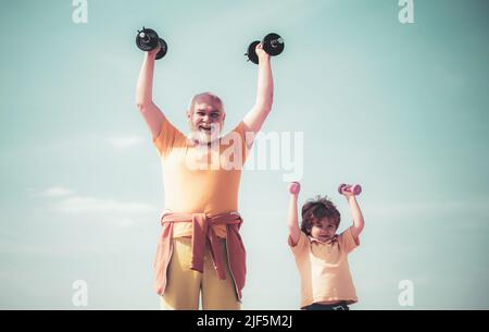 Sport für kleine Kinder. Senioren und Kinder trainieren am blauen Himmel. Vater und Kinder trainieren. Sport für Kinder. Stockfoto