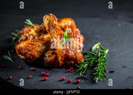 Im Ofen gebackene Hähnchendrumsticks mit Kräutern und Gewürzen auf schwarzem Hintergrund Stockfoto