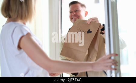 Frau erhält Paket vom Kurier mit Herz vor der Haustür Stockfoto