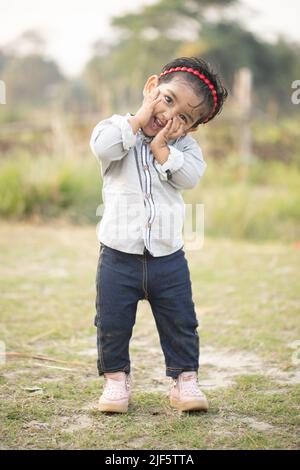 Ein süßes kleines Engel Baby Mädchen mit einem schönen Lächeln, weibliche Blumen menschliches Gesicht Freude im Freien Park klein, Sweet SmilingCute, kleines Mädchen ist sehr süß Stockfoto