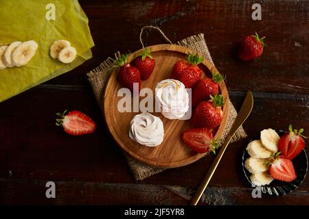 Marshallows mit Bananen- und Erdbeergeschmack auf Holzplatte. Gesunde Lebensmittel, natürliche zuckerfreie Vanillefutter Stockfoto