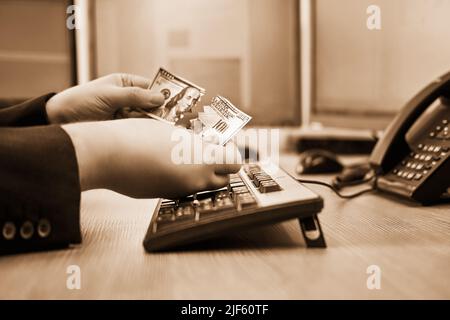 Ein Geschäftsmann mit zerrissenen Geldmitteln in den Händen arbeitet an einer Computertastatur an einem Schreibtisch aus nächster Nähe Stockfoto