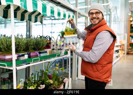 Ein Mann in einem Gartencenter wählt eine Topfpflanze für sein Zuhause Stockfoto