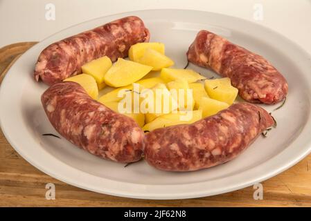 Verbinden Sie Würste mit frisch gebackenen Kartoffeln auf Holzschneidebrett isoliert auf weiß mit Kopierplatz. Stockfoto