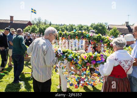 Die Leute bereiten sich vor, um den Mittsommerstab in malmkoping, Schweden, zu schmücken Stockfoto