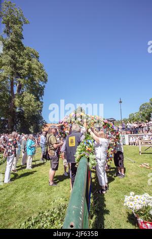 Die Leute bereiten sich vor, um den Mittsommerstab in malmkoping, Schweden, zu schmücken Stockfoto