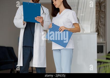 Nahaufnahme von zwei Kollegen, die über die Patientendiagnose sprechen, stehen in der Klinikhalle Stockfoto