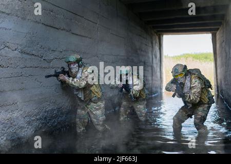 Drei militärische Söldner während einer Spezialoperation im unterirdischen Bunker. Collage - ein Modell in drei Posen. Konzentriere dich auf den linken Soldaten. Stockfoto