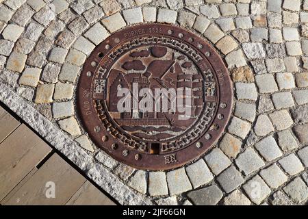 BERGEN, NORWEGEN - 23. JULI 2020: Dekorative Schachtabdeckung aus Gusseisen im Stadtteil Bryggen in Bergen, Norwegen. Es ist ein UNESCO-Weltkulturerbe. Stockfoto
