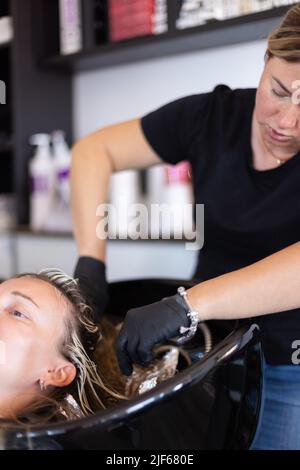 Friseur Nehmen Sie die Folie mit Haarfärbemittel aus den Haaren des Kunden. Stockfoto