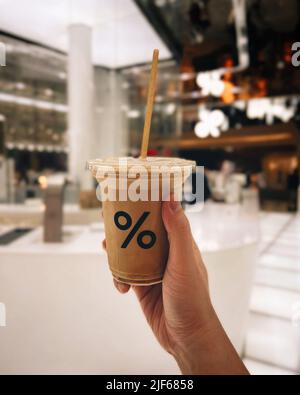 Latte Kaffee-Papiertasse vor Flusshintergrund vor dem Arabica-Café ist berühmt und beliebt bei Touristen Stockfoto