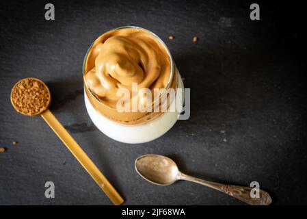 Dalgona Kaffee. Koreanischer Stil Kaffee-Eisgetränk auf dunklem Hintergrund. Instant-Kaffee mit Zucker und Wasser für ein leckeres Frühstück. Sehr modisch CO Stockfoto
