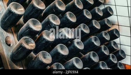 Glasflaschen mit Wein bedeckt mit Schicht von Staub im Weinkeller liegen für den Prozess der Alterung und Reifung des Weins. Stockfoto