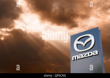 AUGSBURG, DEUTSCHLAND – 16. JUNI 2022: Werbeschild der Automarke MAZDA vor einem wolkenbewölkten Himmel Stockfoto