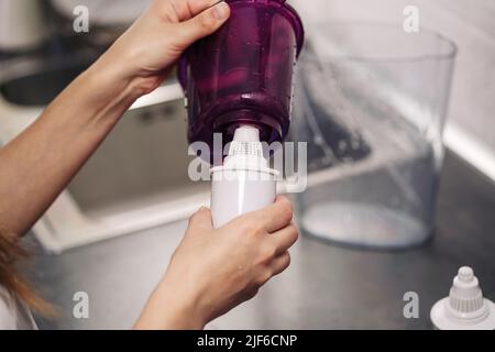 Frau, die den Filter in einem Wasserkrug ersetzt. Weibliche Hand entfernt eine alte Wasseraufbereitungspatrone aus einem Krug. Der Prozess, einen alten Wat zu ersetzen Stockfoto