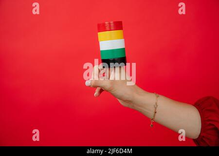 Weibliche Hand hält auf der Fingergruppe der Rolle des Kanals Isolierband auf rotem Hintergrund Stockfoto