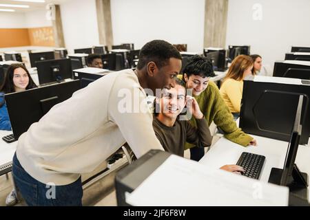 Junge multirassische Studenten mit Computern während der Business-Klasse in der Schule - Fokus auf Center guy Gesicht Stockfoto