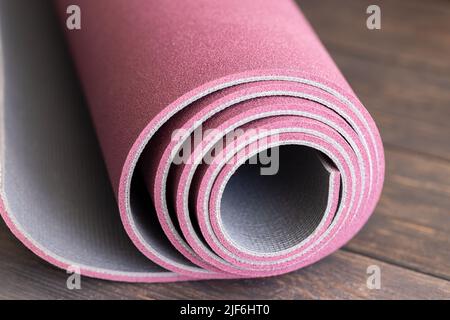 Gerollte Yogamatte auf Holzboden, Konzept für den Start des Ashtanga Yoga. Stockfoto