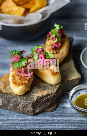 Closeup köstliche Mayan-Polkane-Gericht mit Kürbiskernen und weißen Bohnen Toksel garniert mit eingelegten roten Zwiebeln und Petersilie und serviert auf einem Stück Ro Stockfoto